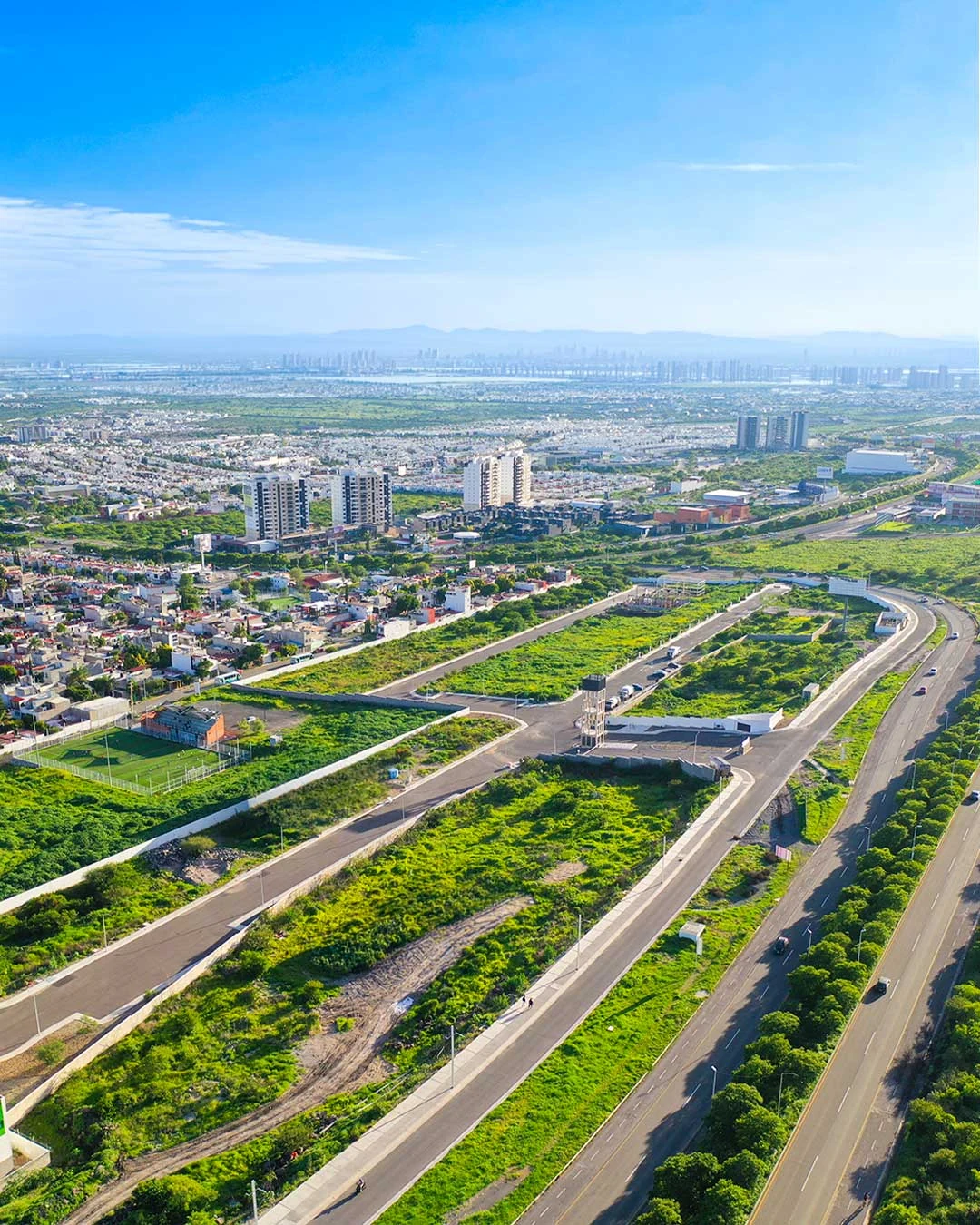 Vista aérea del terreno de Zenayë, con avenidas, áreas verdes y zona urbana al fondo, en El Marqués, Querétaro.